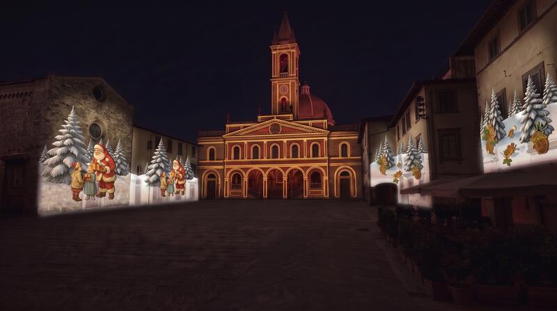 Piazza con chiesa illuminata e scene narrative proiettate sui fronti laterali