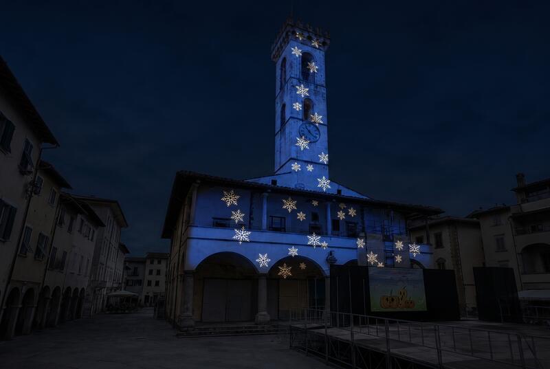 Palazzo civico con torre illuminata in blu scenografico e fiocchi di neve proiettati