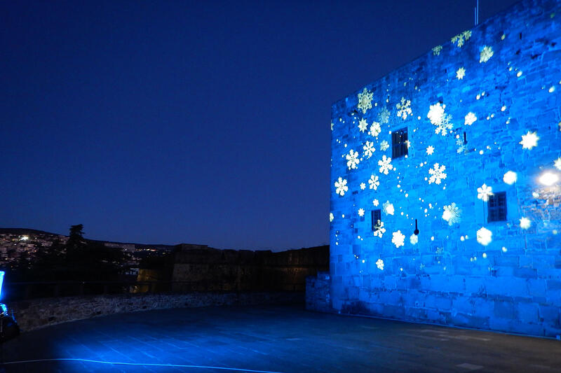 Muratura storica illuminata in blu con fiocchi di neve proiettati, progetto realizzato